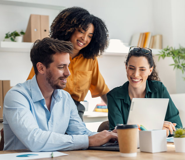 Man and two women looking at laptop working together
