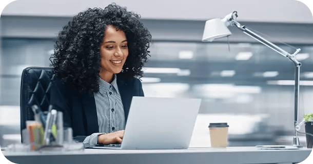 an image of a women in an office setting sitting at a laptop computer working